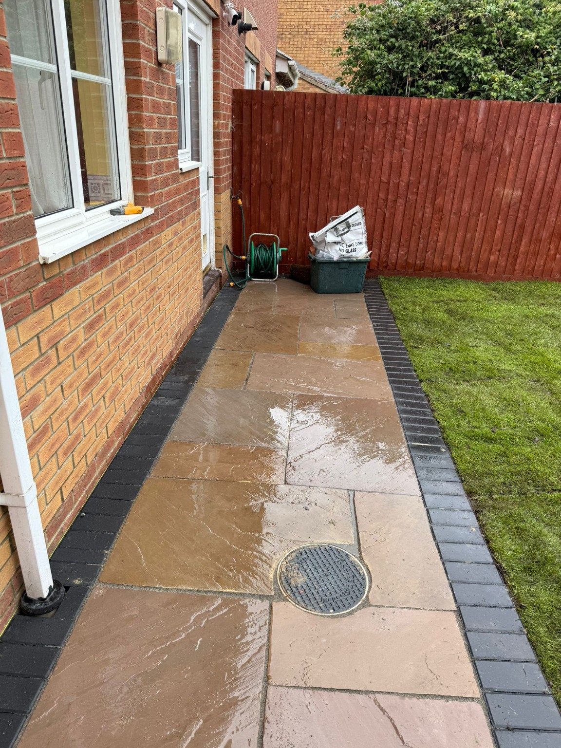 Indian sandstone paving with charcoal edging beside the house and lawn