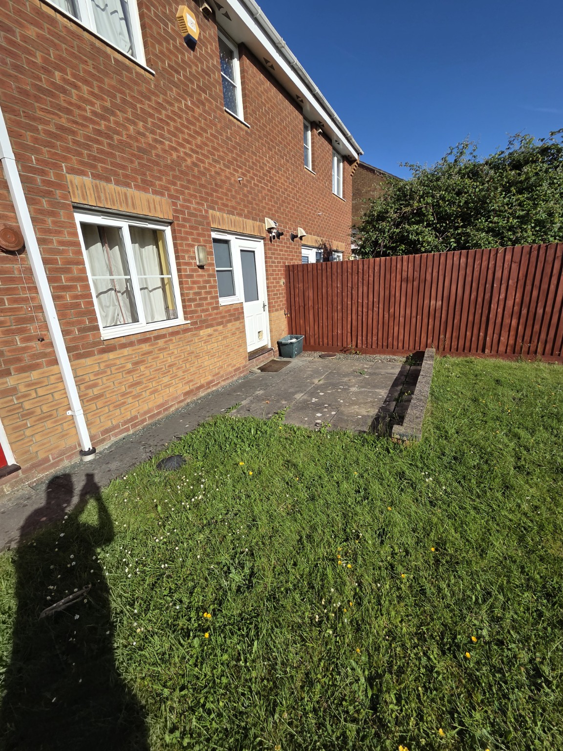 Original concrete patio and raised lawn beside the back door