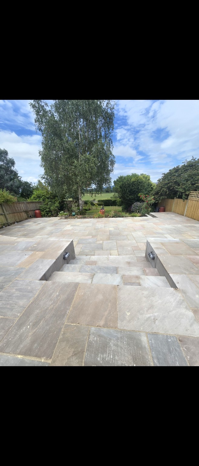 Indian sandstone paving across two patio levels with central steps and wall lights in Taunton