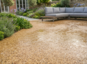 Seamless resin-bound patio surface draining rainwater cleanly in a summer garden