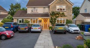 Multiple cars parked neatly on a residential driveway with clear edges, lighting and a safe path to the front door