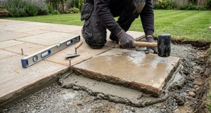 Landscaper laying sandstone paving slabs on a compacted sub-base