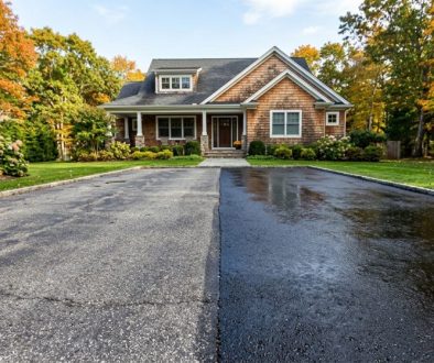 Asphalt driveway showing faded gray pavement beside a freshly sealcoated black surface