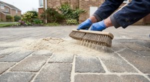 Kiln dried sand being brushed diagonally into block paving joints after cleaning